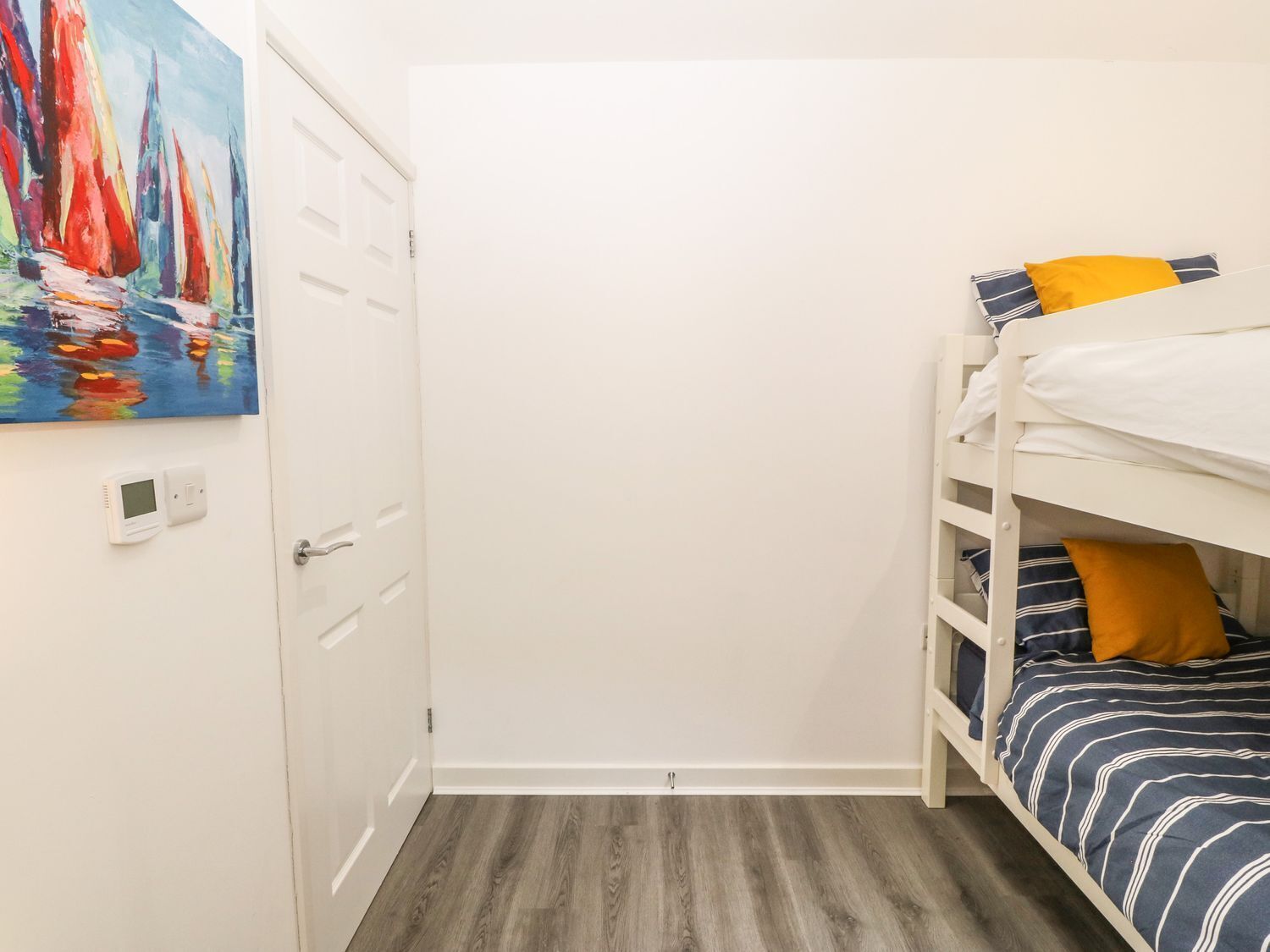 Una habitación con literas, una puerta y un cuadro en la pared.