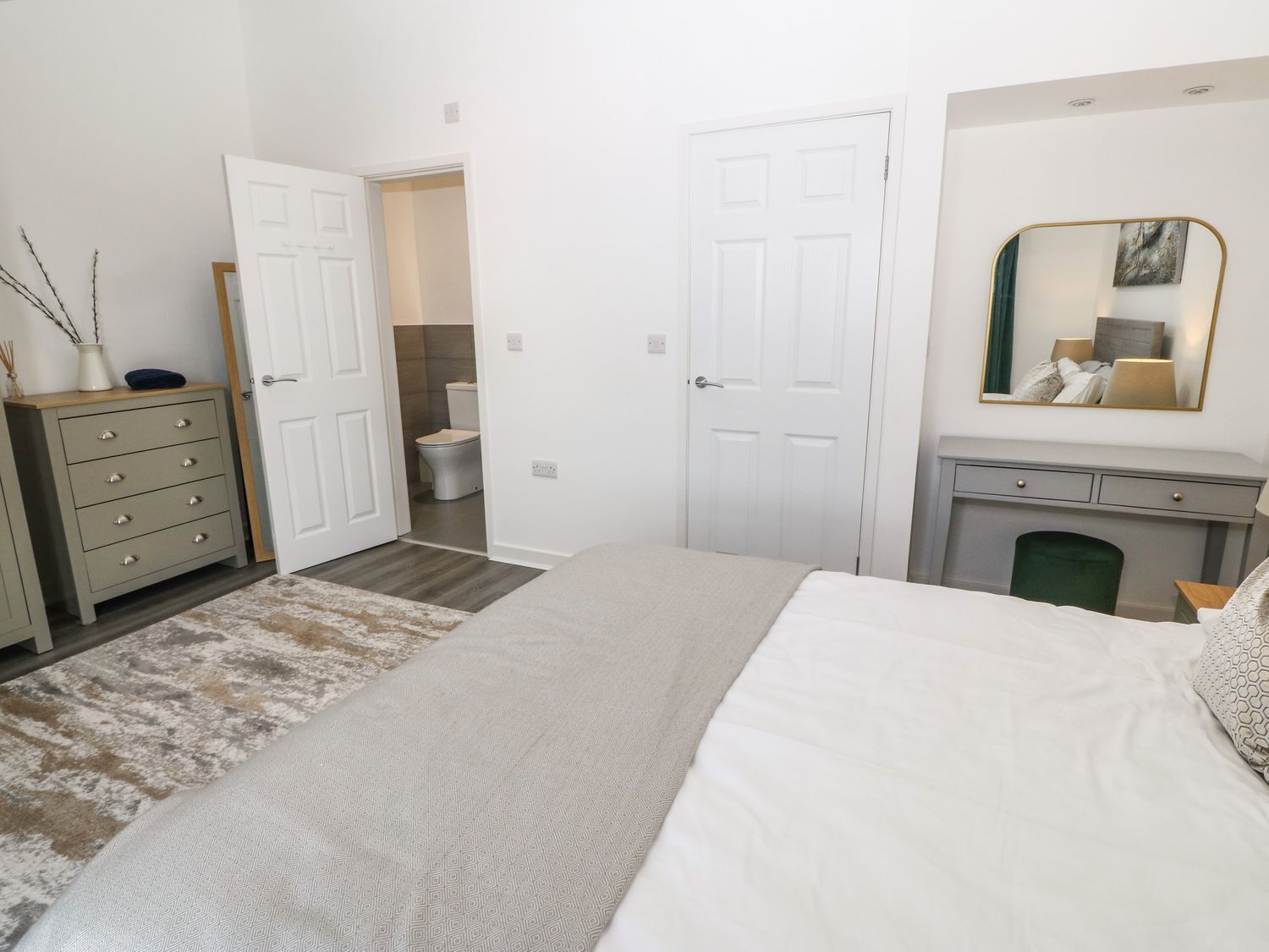 Une chambre à coucher avec un lit, une commode et une salle de bain visible à travers une porte ouverte.