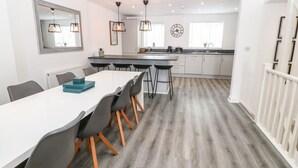 Une cuisine moderne avec des meubles blancs, un îlot central et des luminaires suspendus.