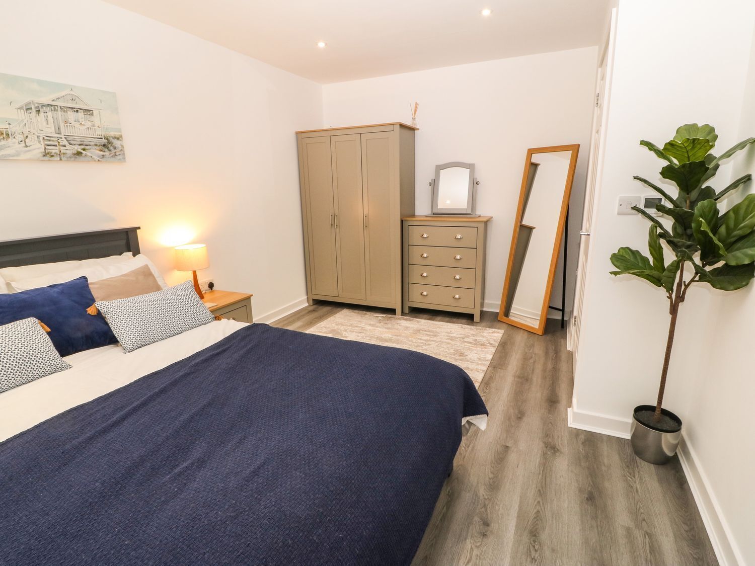 Quarto com cama, penteadeira, guarda-roupa, espelho e planta em vaso.