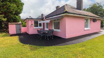A pink house with a patio, a small shed, and a chimney.