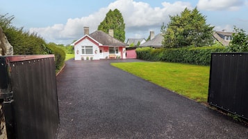 Situated at the end of a gravel driveway, this house offers a serene setting surrounded by well-maintained lawns and hedges.