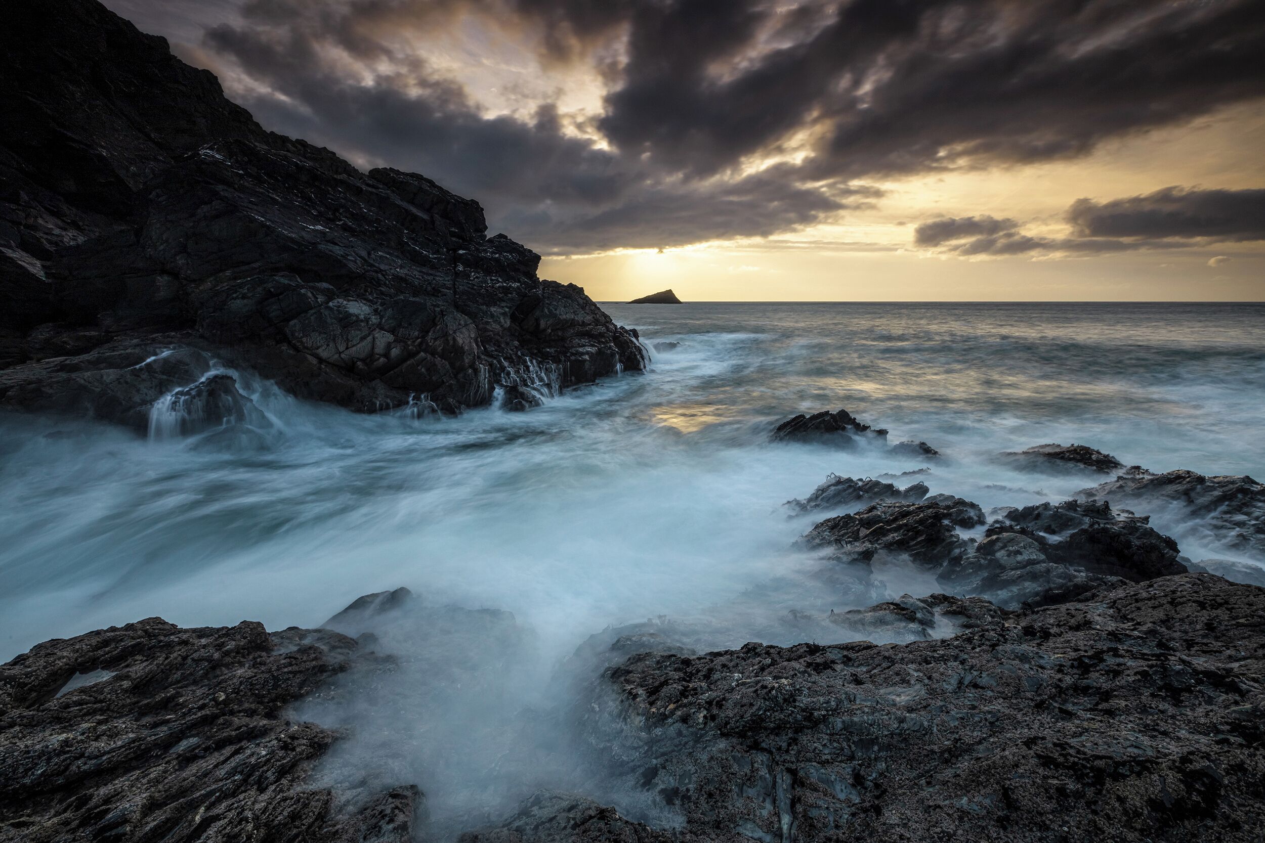 Un paysage côtier caractérisé par un terrain rocheux et une étendue d’eau.