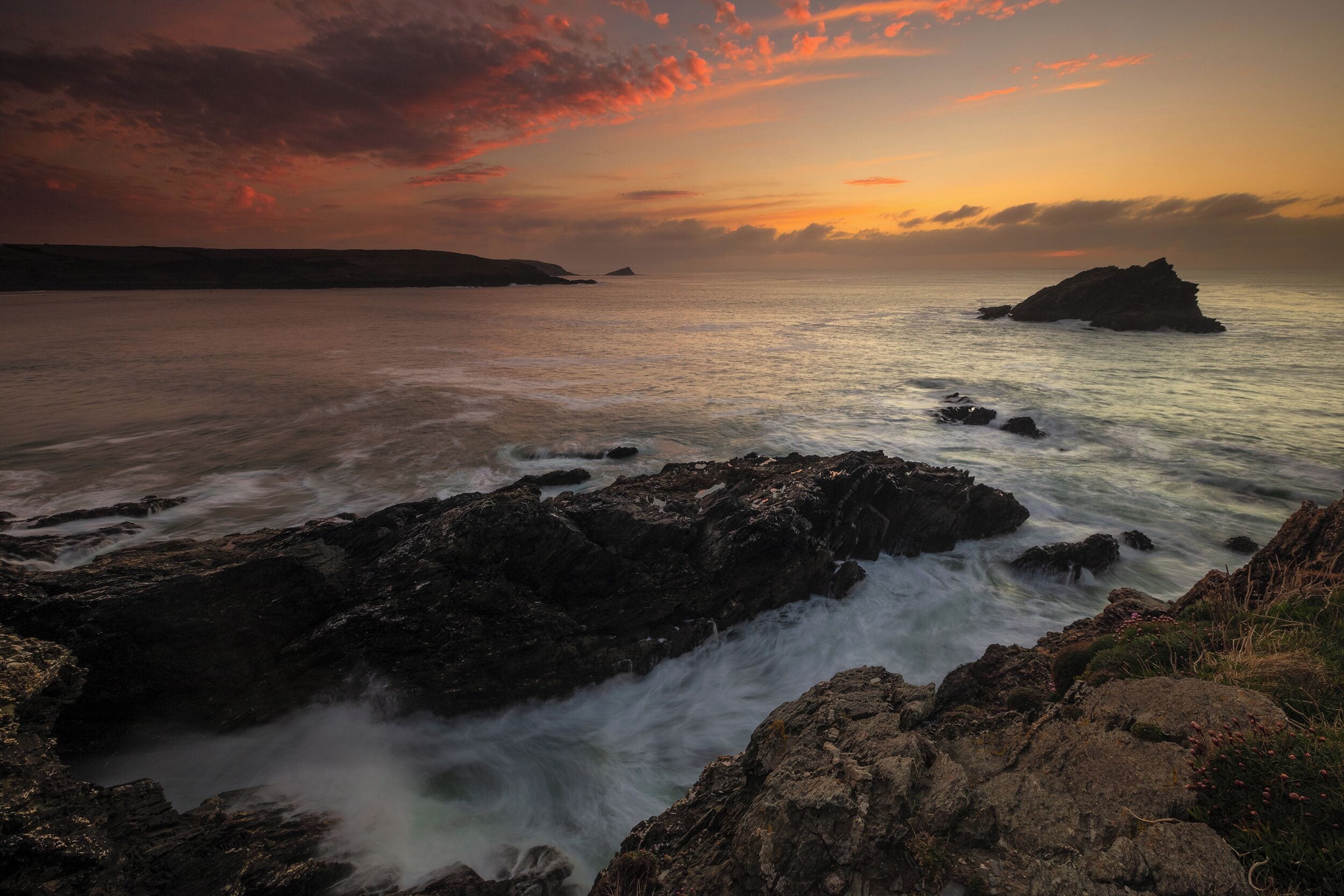 Un paysage côtier caractérisé par un terrain rocheux et une mer calme.