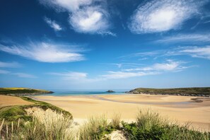 A coastal landscape with a sandy beach, grassy dunes, and a clear blue sky. - Sandwood Studios (Newquay)