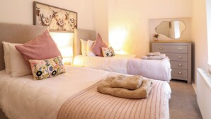 Una camera d'albergo con due letti, una cassettiera, uno specchio e un quadro appeso al muro.