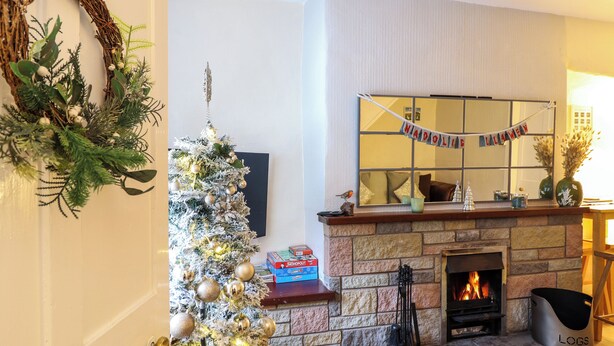 Un soggiorno con camino, un albero di Natale e una mensola decorata con uno specchio e addobbi.
