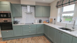 Una cocina moderna con armarios verde claro, un horno de acero inoxidable y piso de madera.