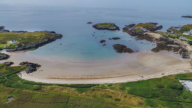 An aerial view of a coastal area with a sandy beach, rocky outcrops, and scattered houses. - Bodior Garden Cottage (Holyhead)