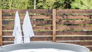 A hot tub with two white towels hanging on a wooden fence. - Bodior Garden Cottage (Holyhead)