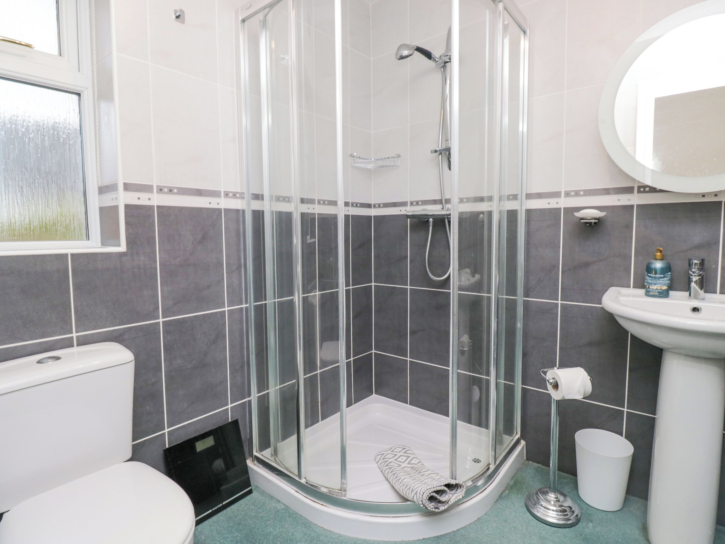 Un baño con ducha de vidrio, inodoro, lavabo y espejo.