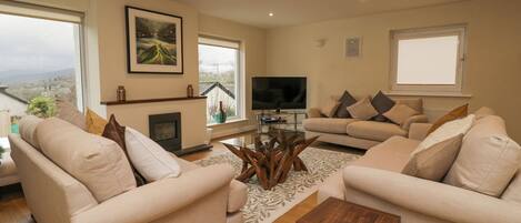 A living room with two sofas, a coffee table, a flat-screen TV, and a fireplace.