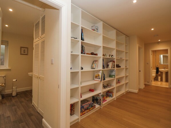 A spacious room with a large white shelving unit filled with books and board games. - Whimhowe (Windermere)