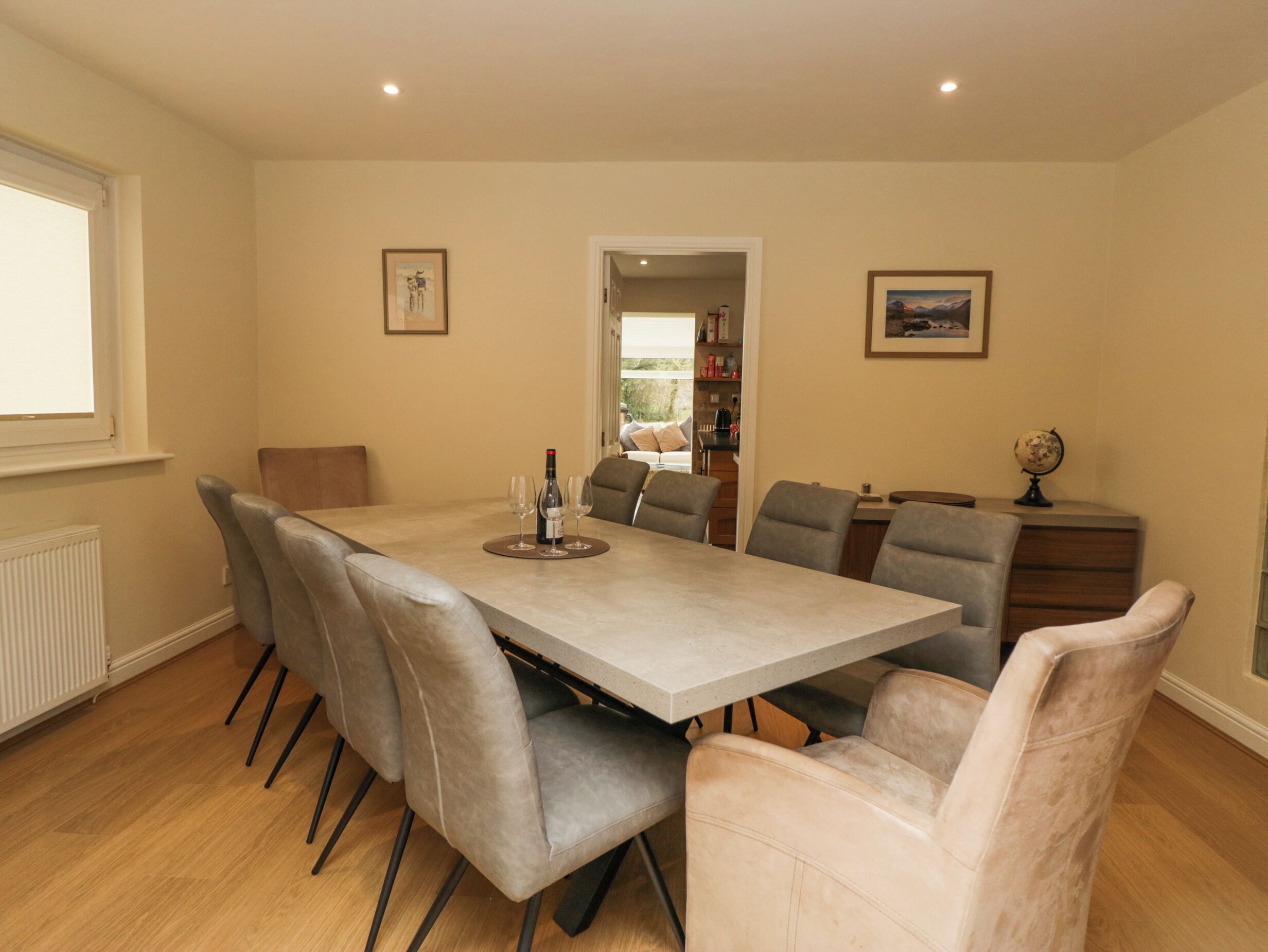 Une salle à manger avec une table rectangulaire, six chaises et une bouteille de vin.
