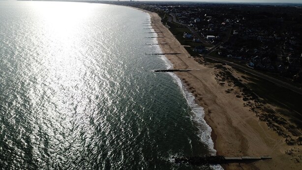 An aerial view of a beach with a long stretch of sand and a clear view of the ocean. - Bayview Cottage (Bournemouth)