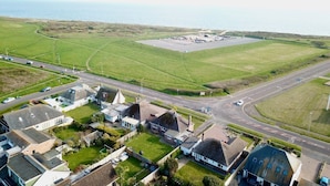 An aerial view of a residential area with houses, a road, and a large open field. - Bayview Cottage (Bournemouth)