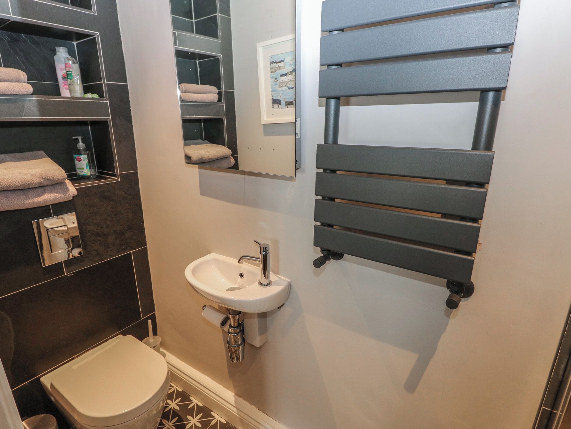 A bathroom with a white sink, a toilet, and a towel rack.