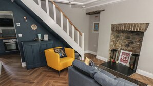 A living room with a staircase, a fireplace, and a kitchen in the background. - Min-y-ffordd (Newport)