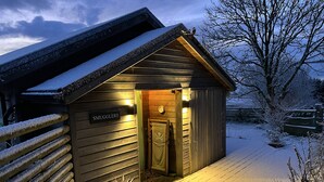 A wooden cabin with a sign reading "SMUGGLERS" and a door with a skull and crossbones emblem. - Smugglers (Bodmin)