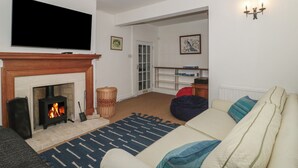 Una sala de estar con chimenea, televisor, sofá y estantería.