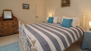 Un dormitorio con cama, cómoda y dos lámparas fijadas a la pared.