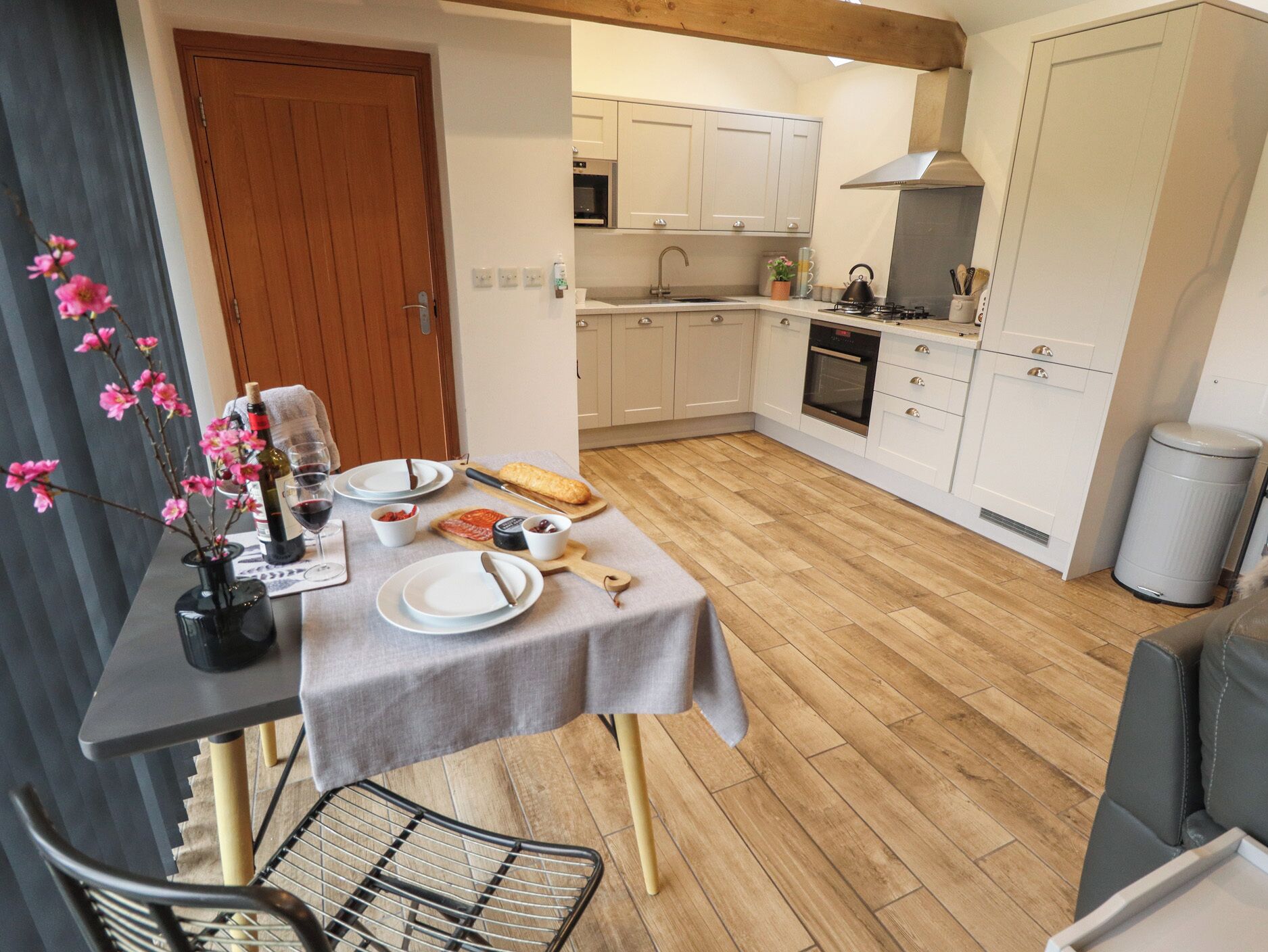 A modern kitchen with white cabinets, a wooden floor, and a dining area with a table set for two.