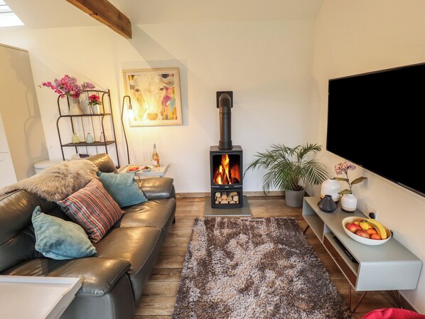 Una sala de estar acogedora con chimenea, un sofá, una mesa de centro y un televisor.