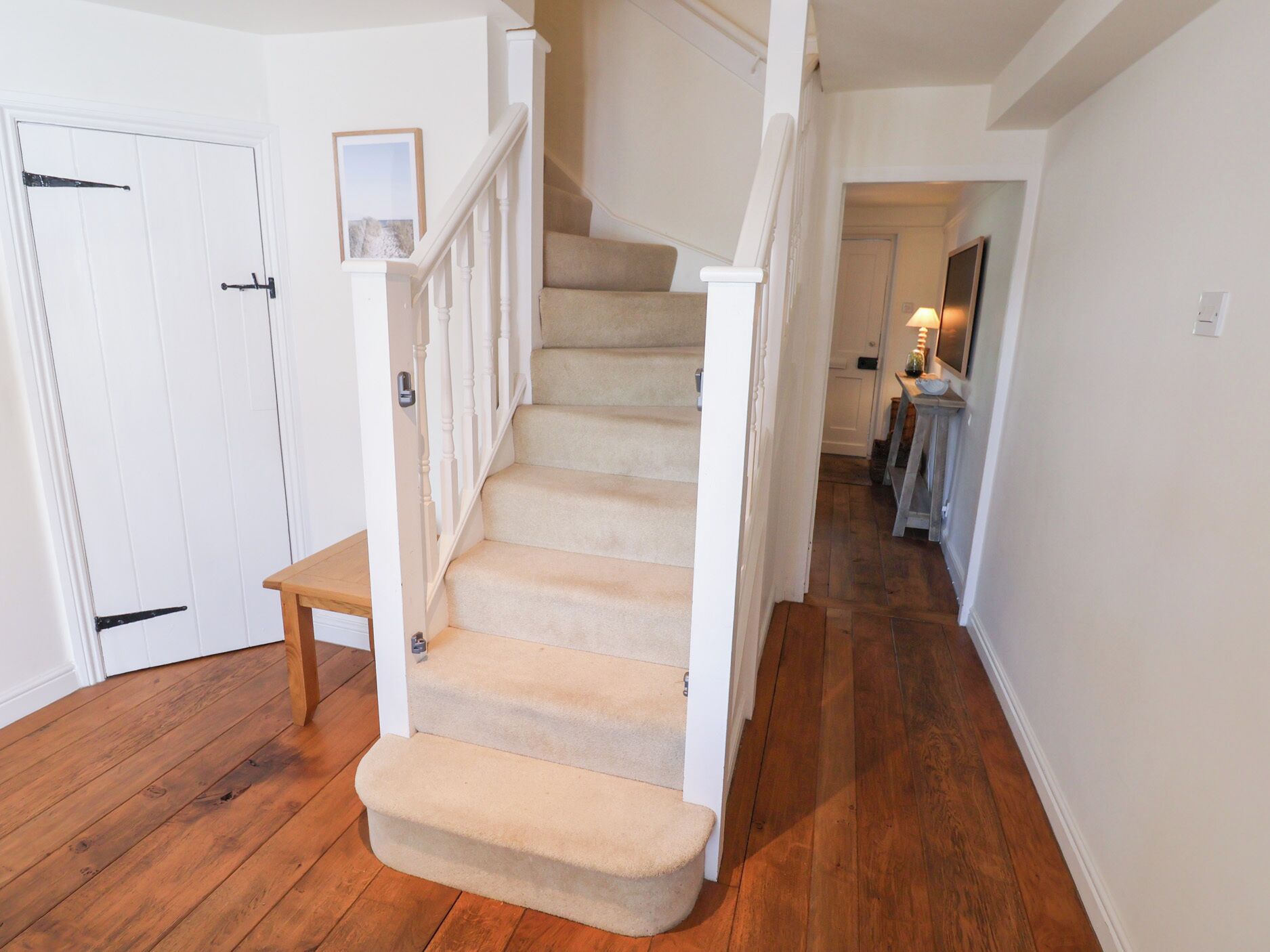 Un escalier avec une rampe en bois et des marches recouvertes d’une moquette beige, menant à l’étage supérieur.