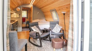 Un intérieur chaleureux, avec des murs en bois et un plafond voûté, un lit, deux fauteuils à bascule et une petite table.