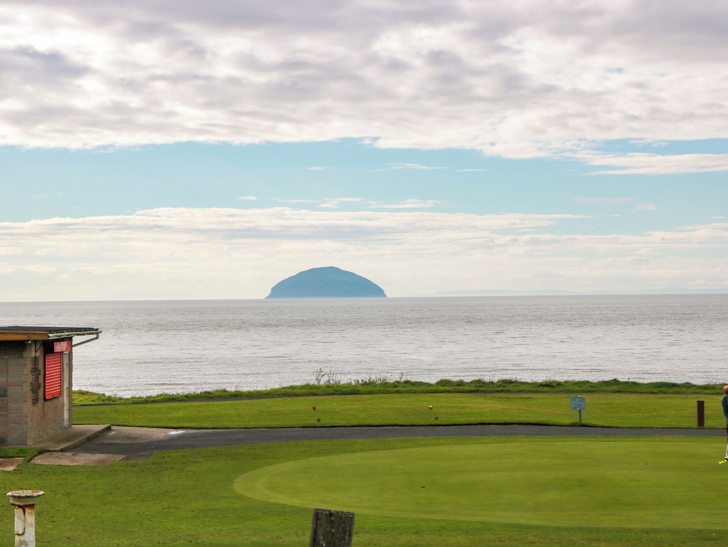 A coastal view with a grassy area, a road, and a body of water.