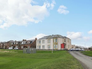 A residential building with a flat roof, multiple windows, and a red door.