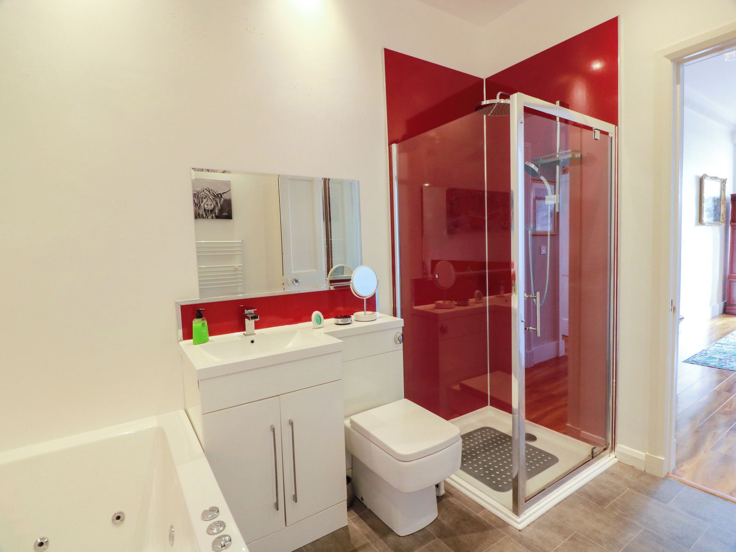 A modern bathroom with a glass-enclosed shower, a white sink with a mirror, and a toilet.