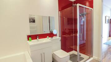 A modern bathroom with a glass-enclosed shower, a white sink with a mirror, and a toilet.