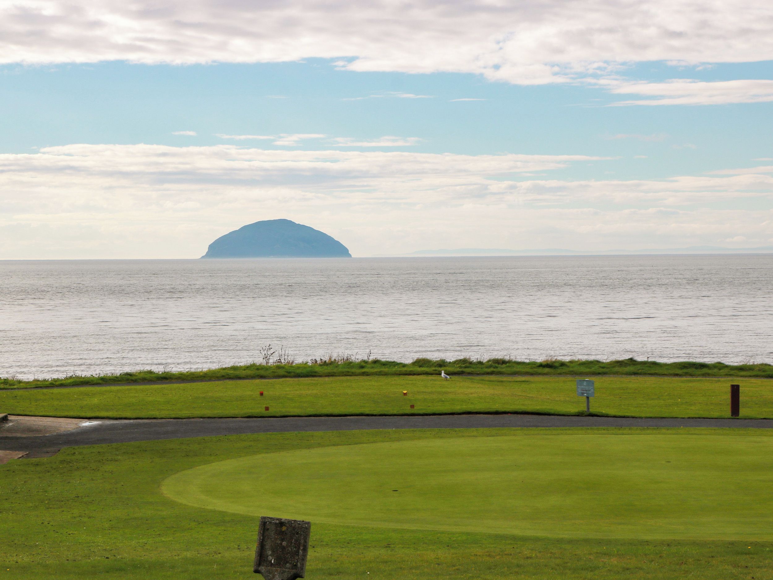 A golf course with a water body and an island in the distance.