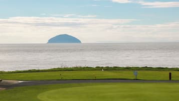 A golf course with a water body and an island in the distance.