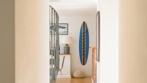 Ein Flur mit Holzboden, einem blauen Surfbrett, einer Lampe und einem gerahmten Bild an der Wand.