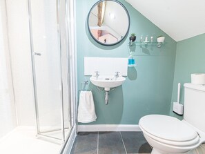 Une salle de bain avec une douche à parois de verre, un lavabo blanc, un miroir et des toilettes.