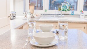 Un plan de travail de cuisine avec deux bols blancs et deux verres d’eau, une cuillère et un vase décoratif.