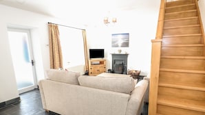 A living room with a sofa, a fireplace, a television, and a staircase. - Bryn Uchaf (Tyn-y-Gongl)