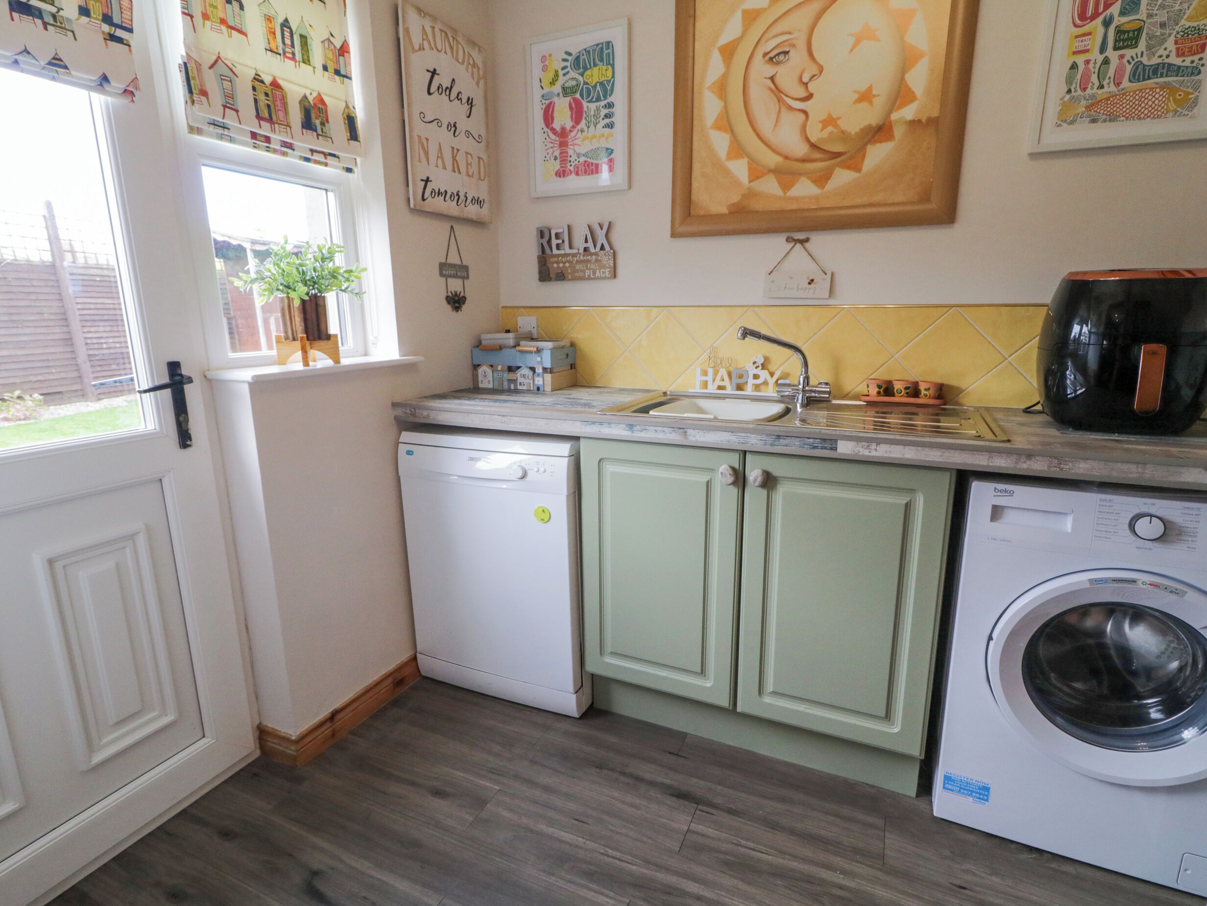 A kitchen with a washing machine, a sink, and a coffee maker.