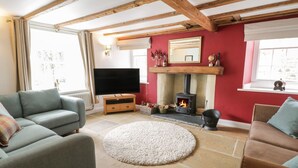 A cozy living room with a fireplace, stone flooring, and wooden beams on the ceiling. - Rorty Crankle (Pickering)