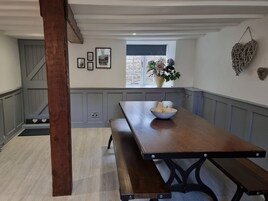 Una cocina con una mesa de madera, un banco y una ventana con un florero.