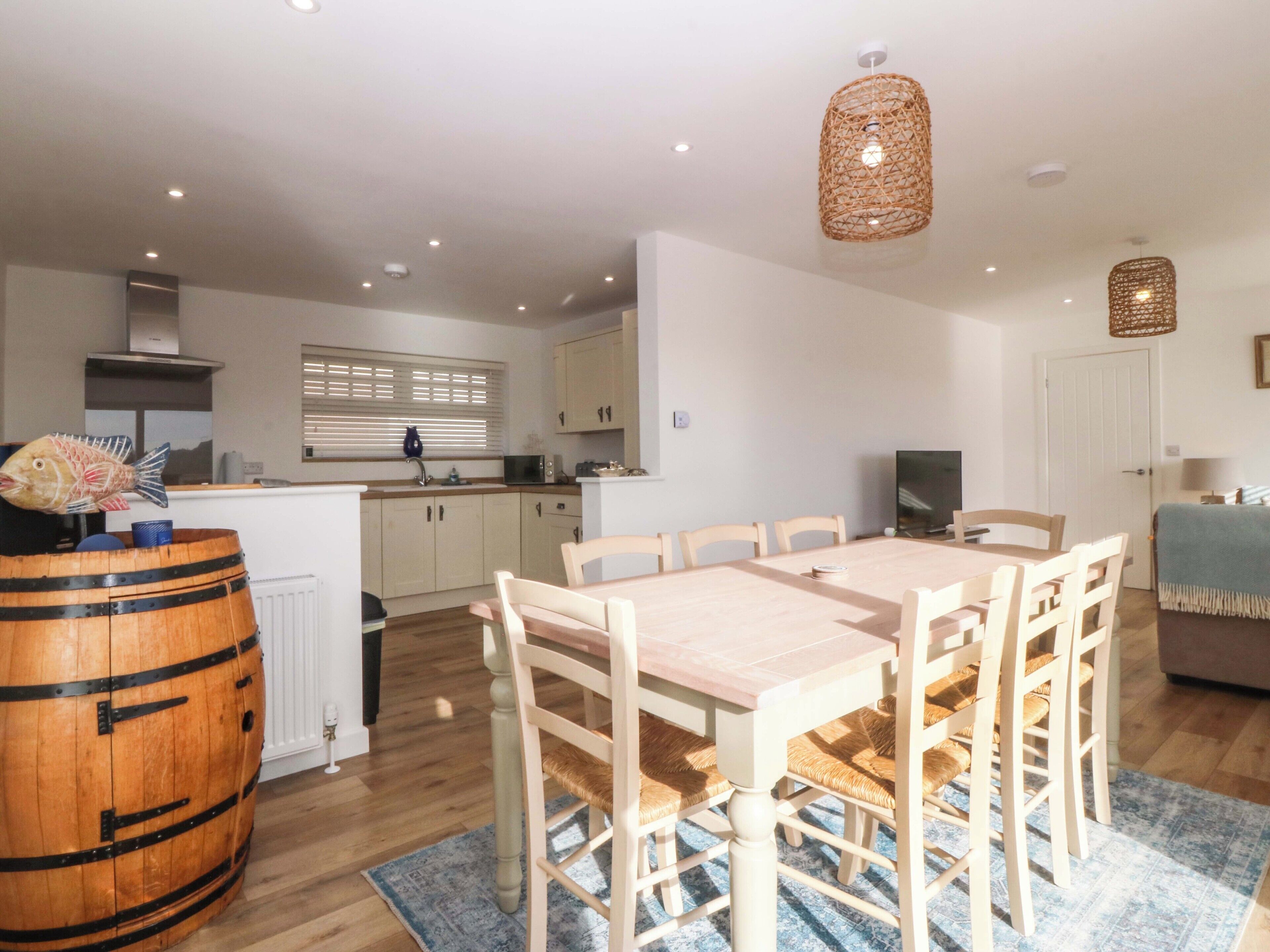 Une cuisine moderne avec des meubles blancs, une table à manger en bois et un grand tonneau en bois.