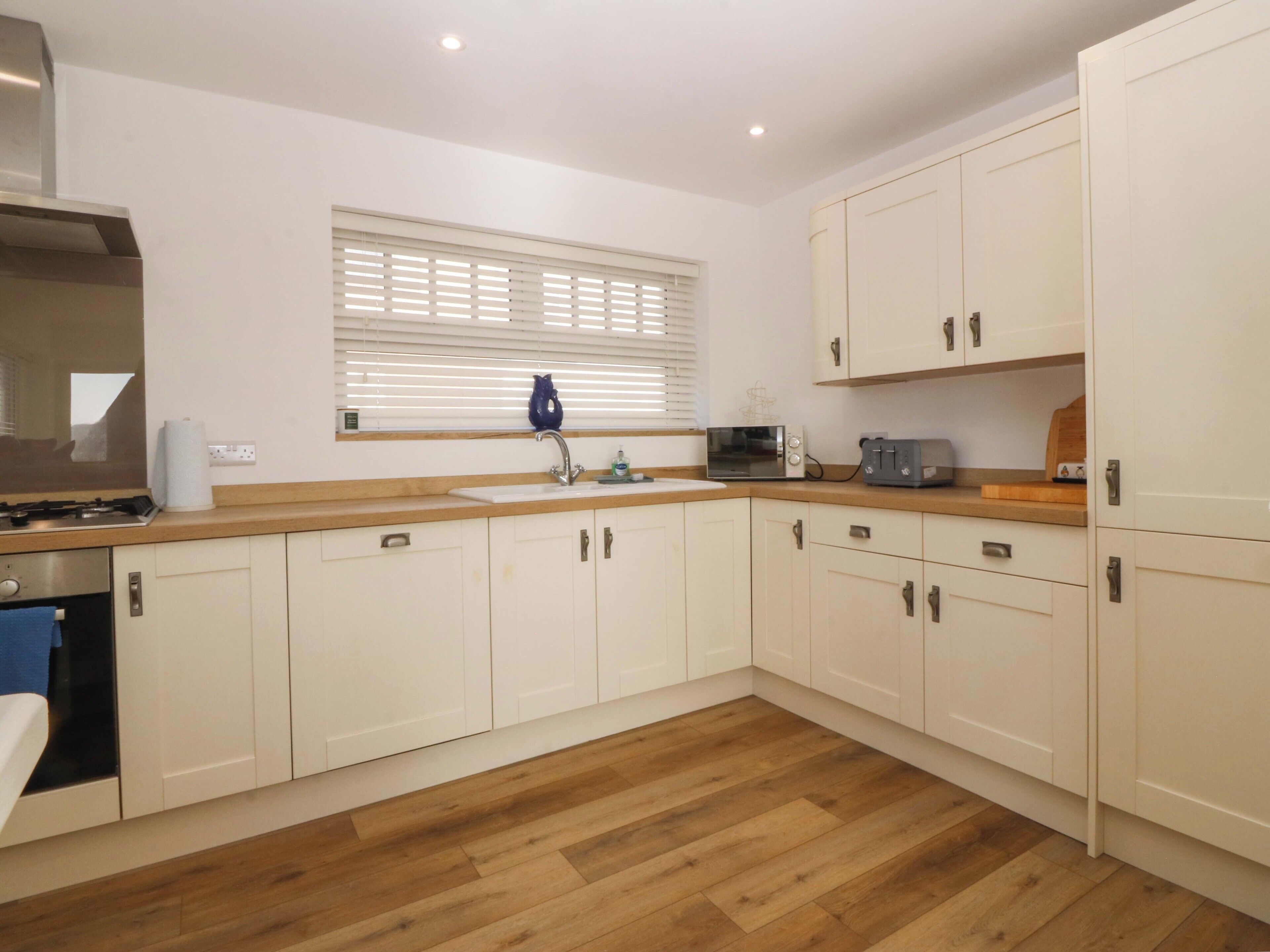 A modern kitchen with white cabinets, a wooden countertop, a built-in microwave, and a gas stove.