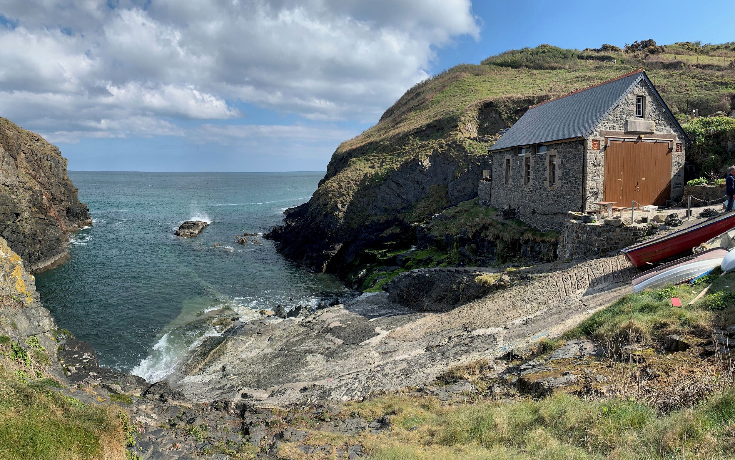 A stone building with a sloped roof near a rocky coastline.