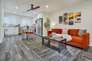 A modern kitchen with white cabinets, a dining area with a wooden table and chairs, and a living room with an orange sofa and a coffee table. - Terrific Smoke-Free Place in Heart of Kings Beach walking distance to Lake (Kings Beach)