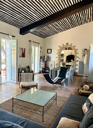 A spacious living room with a stone fireplace, a glass coffee table, and a modern sofa.