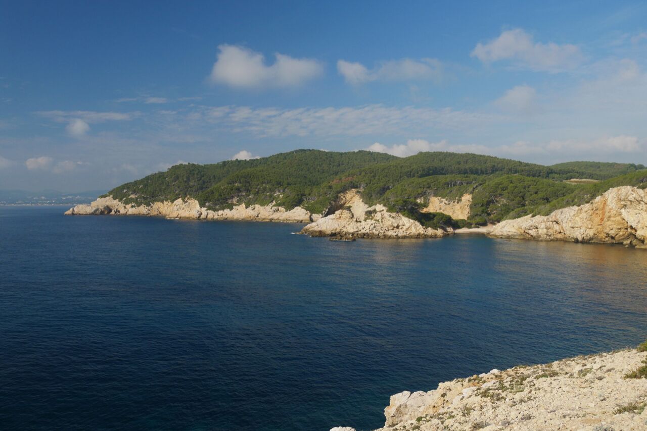 A coastal landscape with rocky cliffs and a clear blue sea.