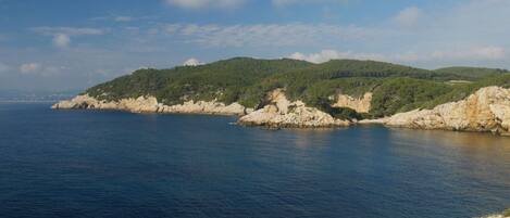 A coastal landscape with rocky cliffs and a clear blue sea.