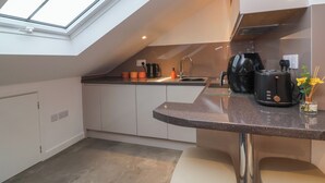 Eine moderne Küche mit Dachfenster, einer Kaffeemaschine, einem Toaster und einem Spülbecken.